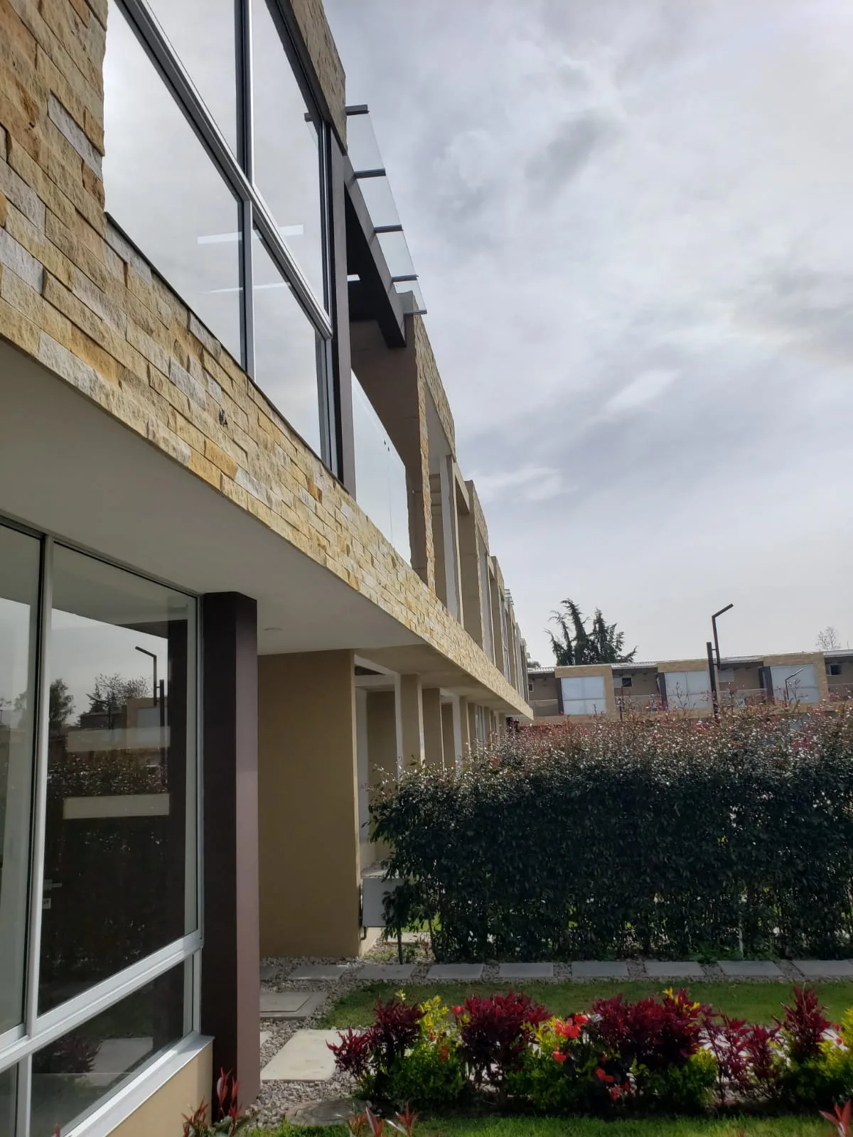 Foto real del detalle de balcones con piedra natural y barandas de vidrio templado en Bosco Reservado